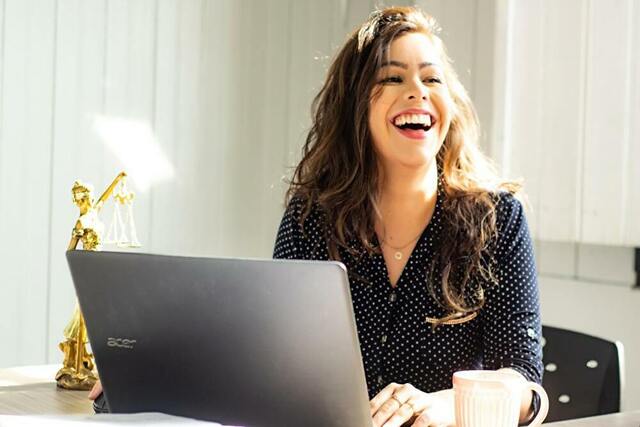 笑顔でパソコンの前に座る女性