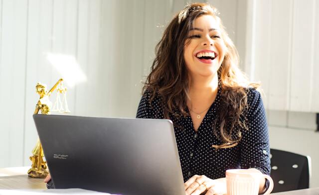 笑顔でパソコンの前に座る女性